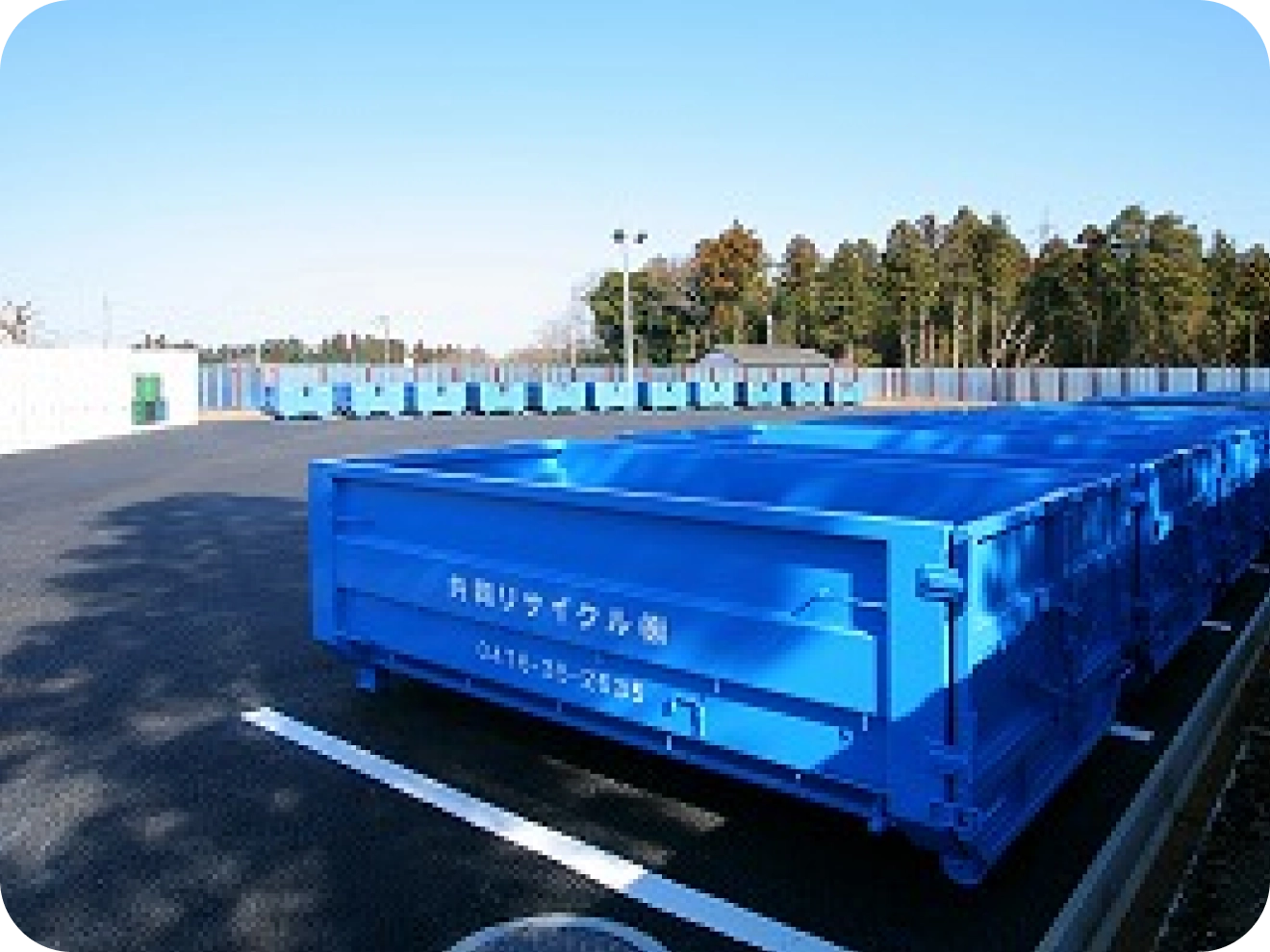 緑色のヘルメットをかぶった作業員がフォークリフトを操作し、圧縮・梱包されたアルミ缶の塊を運搬している